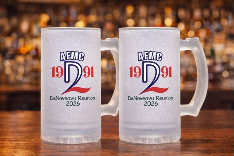 Two frosted beer mugs with AFMC 1991 DeNoverau Reunion 2026 logo on a bar background.